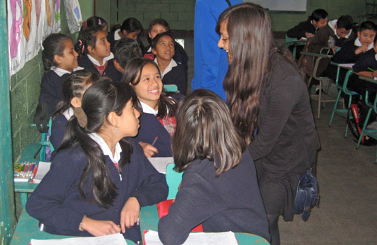 Girls in school uniform talking together in a classroom