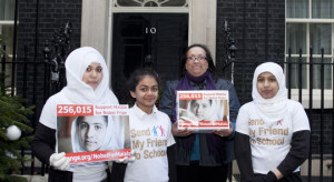 Woman and three girls in Send My Friend to School t shirts with petition box outside 10 Downing Street