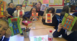 Children in a classroom holding up colourful door artwork