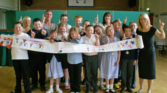 Adults and children holding up giant scarf artwork