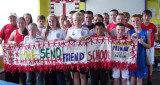 Schoolchildren holding up fabric banner saying 'Send My Friend to School'