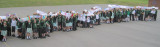 Long line of children in a playground, holding up scarft artwork.