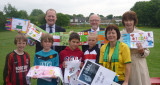 Adults and children in football kit, displaying artwork.