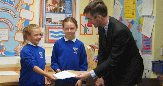 Man being presented with artwork by two schoolgirls