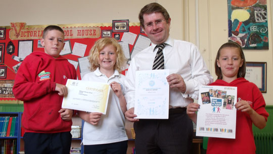 Man with schoolchildren holding up artwork.