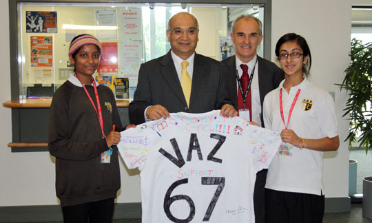 Two men and two girls hold up a decorated t-shirt.