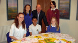 Young people in an office with MP, artwork spread out on table.