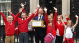 Adult and children in school uniform outside 10 Downing Street