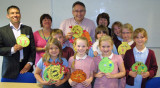 Four adults and group of children with gold medal artwork.