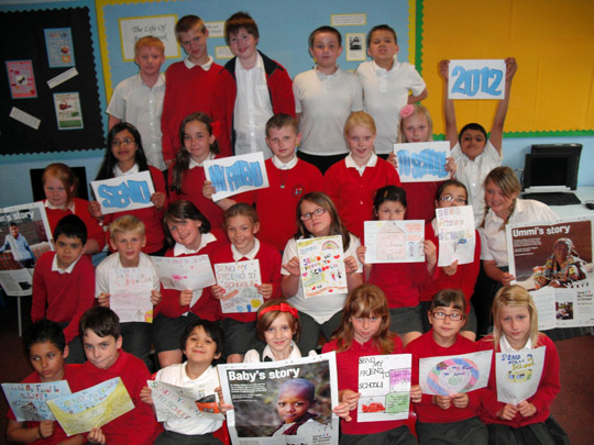 Large group of school children holding up Send My Friend to School posters