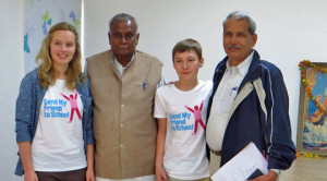 Teen girl and boy wearing Send My Friend to School t shirts with two adult men, all smiling at the camera.